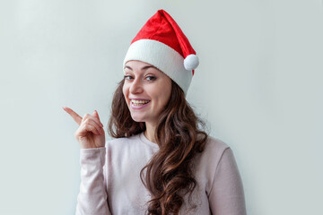 Beautiful girl in red Santa Claus hat presenting and pointing showing finger hand isolated on white background. Young woman Christmas and New Year concept. Copy space for product or text