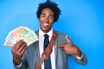 Handsome african american man with afro hair holding south african rand banknotes pointing finger to one self smiling happy and proud