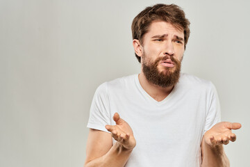 bearded man gesturing with his hands in a white t-shirt aggression light background