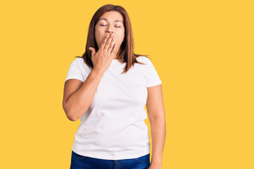 Middle age latin woman wearing casual white tshirt bored yawning tired covering mouth with hand. restless and sleepiness.