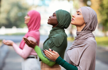 Three Muslim Women Praying Together Standing Outdoors Wearing Traditional Hijab