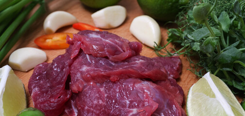 Raw beef sliced on a board with fresh vegetables