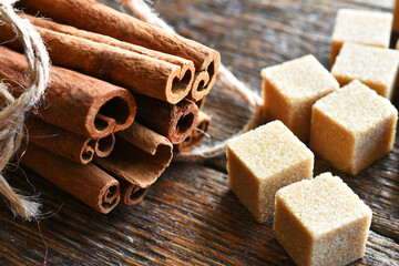 A close up image of fresh cinnamon sticks and brown sugar cubes. 