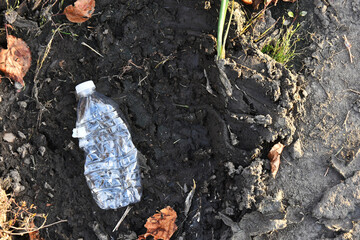 An image of an empty plastic drinking bottle left as litter on the ground. 