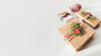 Christmas DIY presents wrapped in craft paper with fir tree branches and red hearts. Decorations on New Year gifts. Festive background. Winter holiday spirit. Banner with copy space.