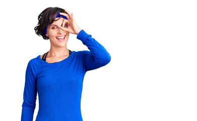 Beautiful young woman with short hair wearing training workout clothes doing ok gesture with hand smiling, eye looking through fingers with happy face.