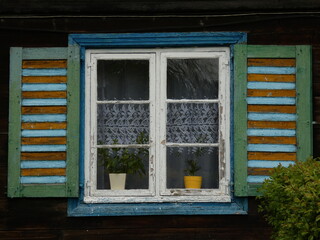 Window of an old rural wooden house with white frames and colorful shutters, Żuławki, Poland