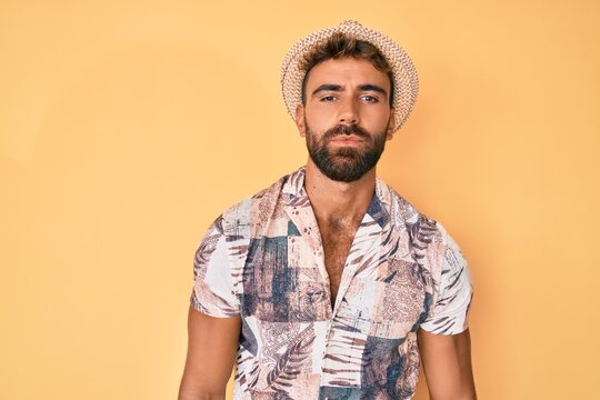 Young hispanic man wearing summer hat relaxed with serious expression on face. simple and natural looking at the camera.