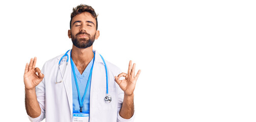 Young hispanic man wearing doctor uniform and stethoscope relax and smiling with eyes closed doing meditation gesture with fingers. yoga concept.