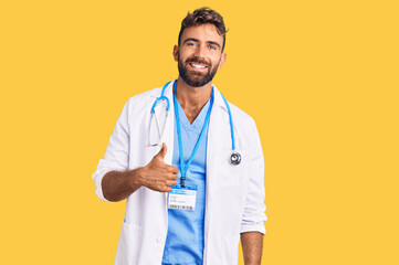 Young hispanic man wearing doctor uniform and stethoscope doing happy thumbs up gesture with hand....