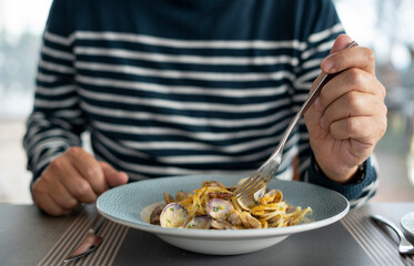 detail male hand eating pasta spaghetti with clams and mullet, Mediterranean food