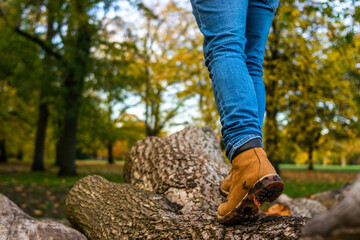 Photo of the legs on a young man wearing mountain boots and jeans walking in a tree trunk during an...
