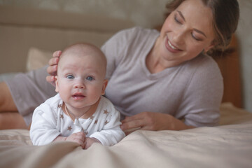 Mother holding infant baby, take care of her 3 months old child at home bedroom . Happy mom carying of her newborn son . Mum love little baby