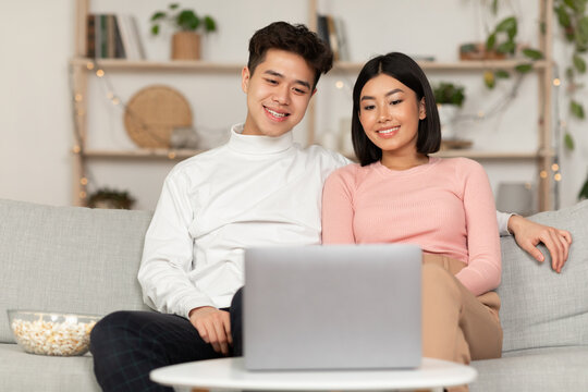 Asian Family Couple Watching Movie On Laptop Online At Home