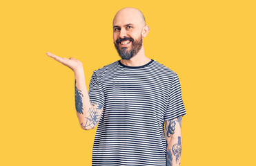 Young handsome man wearing casual clothes smiling cheerful presenting and pointing with palm of hand looking at the camera.