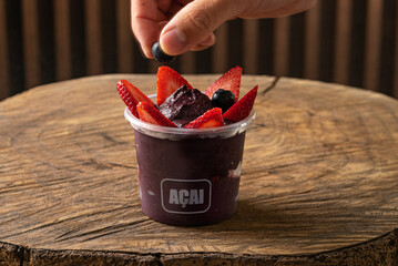 Delicious Brazilian A&ccedil;a&iacute; Cream, in a plastic Cup With Strawberry and blueberry Topping. Summer acai smoothie