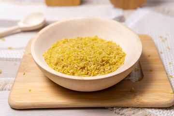 bulgur in a wooden bowl on wooden table, rustic style. Bulgur wheat grains