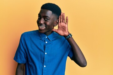 Young african american man wearing casual clothes smiling with hand over ear listening and hearing to rumor or gossip. deafness concept.