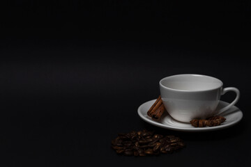 Empty white cup and saucer, coffee beans, cinnamon sticks, anise