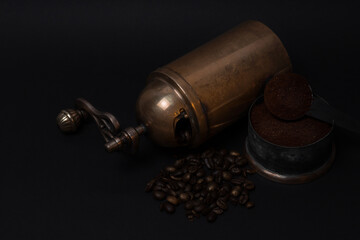 Manual vintage coffee grinder, coffee beans, ground coffee in spoon on black background