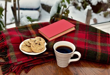 Fresh homemade warm comforting chocolate chip cookies ready to eat and enjoy with cozy mug of tea and relaxing with a book on a cold winter afternoon