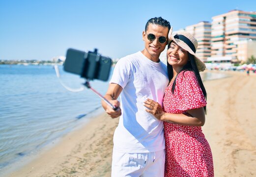 Young latin couple smiling happy making selfie by the smartphone at the beach.