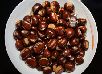A plate full of edible chestnuts ready for roasting, like an October culinary delicacy