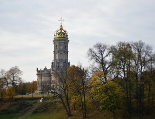 Obraz premium An autumn Russian landscape in yellow and green, with bare trees, beautiful old cathedral and a newly-married couple