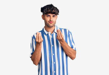Young hispanic man wearing casual clothes doing money gesture with hands, asking for salary payment, millionaire business