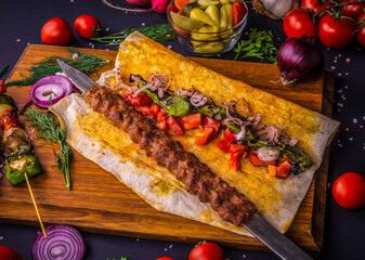 Turkish and Arabic Traditional Ramadan Adana Kebab Roll Wrap serving with vegatable, aubergine salad and hot pepper pickles on rustic wooden background. 