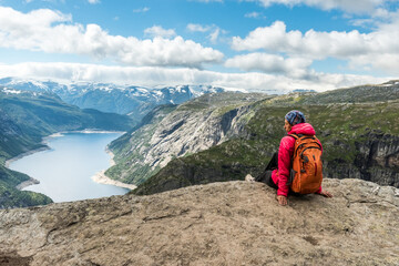 Sporty woman posing on Trolltunga. Happy hiker enjoy beautiful lake and good weather in Norway.