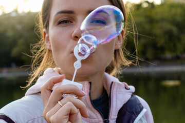 Happy beautiful woman blowing bubbles outside. Spending time like a child. Portrait close up.