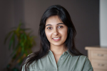 Smiling young adult indian woman looking at camera at home or in office. Pretty lady standing in...