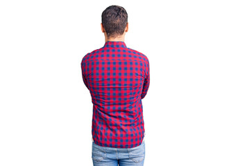 Handsome young man with bear wearing casual shirt standing backwards looking away with crossed arms