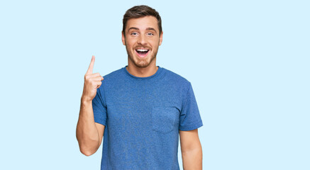 Fototapeta premium Handsome caucasian man wearing casual clothes pointing finger up with successful idea. exited and happy. number one.
