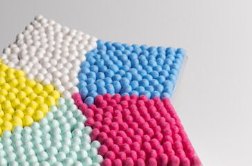 Bright wooden cotton ear sticks or swabs in the box. Colourful things for a good mood. Recycling and sustainability. Close up.