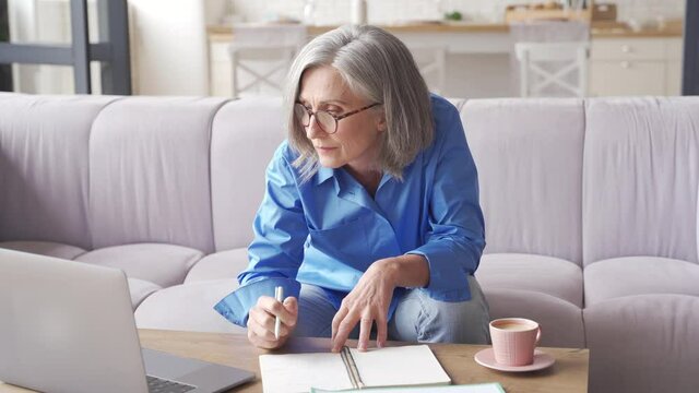 Senior mature older woman watching business training, online webinar on laptop computer remote working or social distance learning from home. 60s businesswoman video conference calling in virtual chat