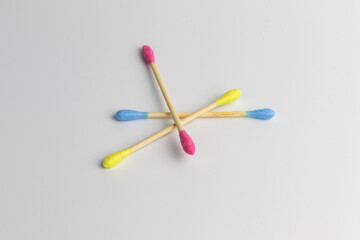 Pink, blue and yellow wooden cotton ear swabs or sticks on white background. Recycling and sustainability problem in everyday reasonable consumption. Colourful lifestyle, isolated, close-up.