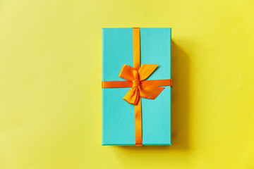 Christmas New Year birthday valentine celebration present romantic concept. Simply minimal design blue gift box isolated on yellow colorful background. Flat lay top view copy space.