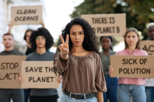 Young woman showing peace gesture, leading group of demonstrators