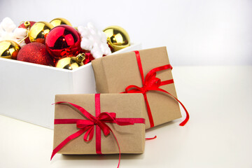 Gifts are placed next to Christmas decorations on a white background. Two gift boxes with red ribbons.