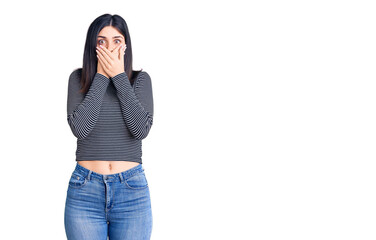Young beautiful girl wearing striped t shirt shocked covering mouth with hands for mistake. secret...