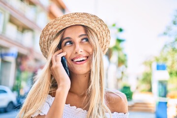 Young blonde tourist girl smiling happy talking on the smartphone at the city.