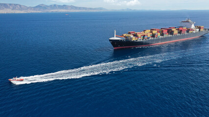 Aerial drone photo of huge container tanker ship carrying truck size colourful containers in deep...