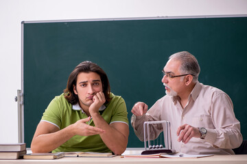 Old professor physicist and young student in the classroom
