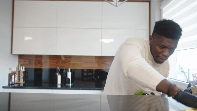 Black man spraying kitchen surface with disinfectant . Germaphobe doing domestic housework. High quality 4k footage
