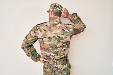 Young caucasian man wearing camouflage army uniform backwards thinking about doubt with hand on head