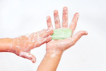 The child washes his hands with soap. A bar of green soap in hands close-up on a white background....
