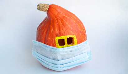 Pumpkin house with a window in a medical mask on a white background. The concept of Halloween, harvest, thanksgiving, stop coronavirus, stay at home. Space for your text