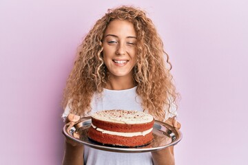Beautiful caucasian teenager girl holding carrot cake winking looking at the camera with sexy...